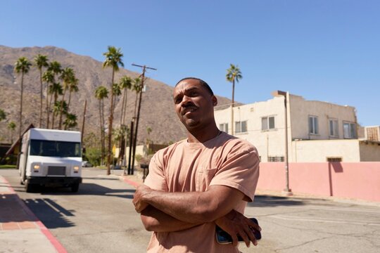 Man Stands Confidently on a Sunny Street With Palm Trees in View