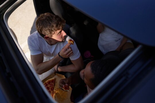 Enjoying a Slice of Pizza During a Car Hangout With Friends