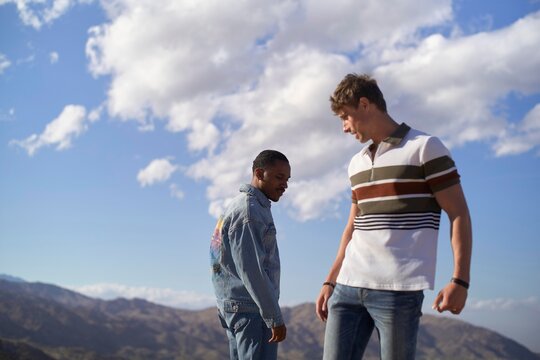 Two men standing on a mountain peak with a blue sky