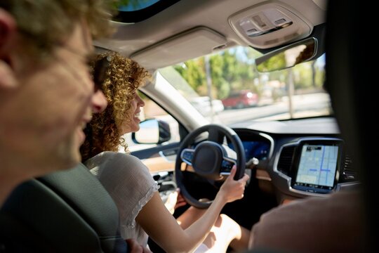 Woman driving a car with a smiling passenger in sunlight