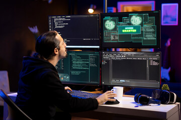 Fototapeta premium Cybercriminal using malicious spyware program to compromise devices and digital networks, gaining passwords. Evil man in criminal den using PC, stealing, exploiting and illegally selling data online