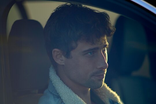 Thoughtful Man Gazing out Car Window During Sunset Drive