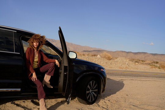 Woman stepping out of a car in a desert landscape