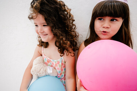 Portrait of two little girl friends happily posing with balloons