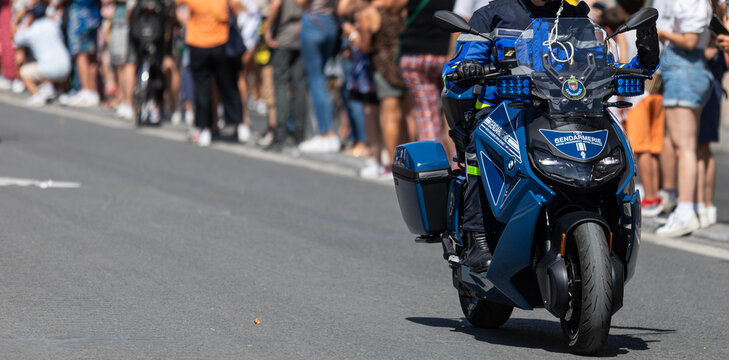 Un motard de la gendarmerie nationale, avec en arri&egrave;re plan des personnes, le 14 juillet 2025 - Paris, France