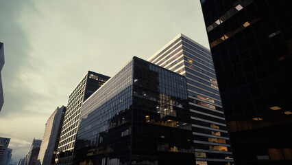 moody glass skyscrapers at dusk, reflective facades and sharp angles on modern corporate towers cinematic atmosphere with brooding sky, mirror windows, © icetray
