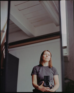 Photographer in studio with film camera in a mirror reflection