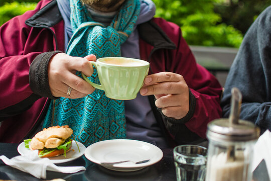 Anonymous man holding latte cup at outdoors cafe