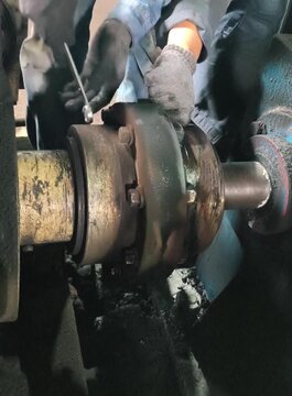 A close-up video of a technician using a wrench to remove bolts from a large industrial gear coupling on a power transmission shaft. Perfect for industrial maintenance and engineering content.