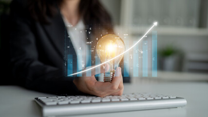 A businessperson holds a light bulb symbolizing creativity amidst graphs illustrating growth in a modern workspace, highlighting the fusion of innovation and productivity. Impute © InfiniteFlow