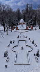 Park dworski w Iłowej w Polsce, w zimowy dzień. Ziemia pokryta śniegiem, widoczna niecka fontanny i ażurowy mur ceglany zwany Bramami Księżyca. Zdjęcie z drona. © boguslavus