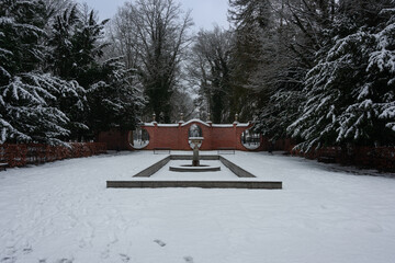 Park dworski w mieście Iłowa w zimowy dzień. Faliste, ażurowe, ceglane ściany, noszące nazwy bram księżycowych wraz ze znajdującymi się w sąsiedztwie nieckami fontann. Ziemię pokrywa śnieg. © boguslavus