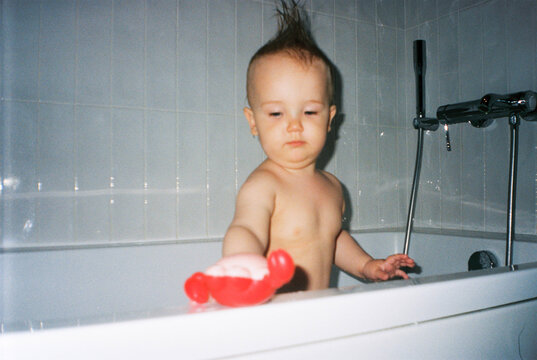 Toddler playing in bathtub with toy  - film analog