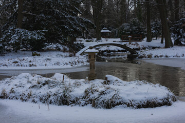Pałac dworski w mieście Iłowa w zimowy dzień. Część japońska parku z elementami architektury parkowej w postaci lampionów, kładek, schodów, altanek, stawu parkowego i strumyka. © boguslavus