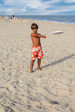 Young boy throws frisbee on the beach