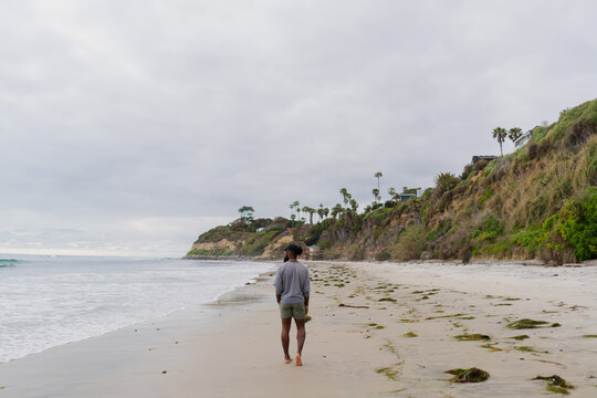 Young Man Looks Towards Oceas While Walking On California Beach