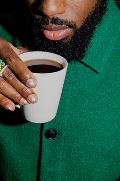 Close Up Young Man Raises Mug to Sip Coffee under Stylized Hard Light.