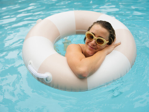 Woman Relaxing in Pool With Swim Float During Sunny Day
