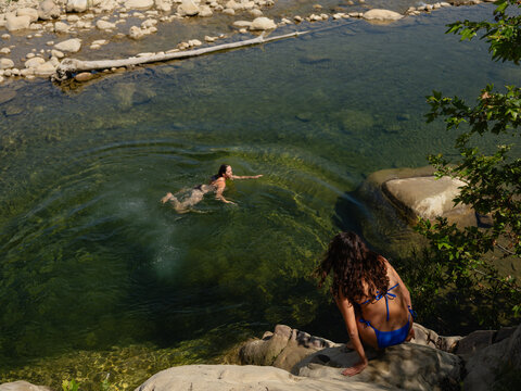 Swimming in a Clear River Surrounded by Rocks and Trees