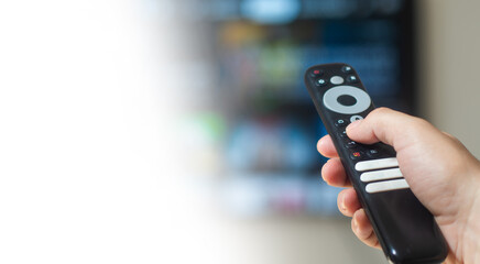 Hand holding television remote control with white background copy space, home media entertainment...