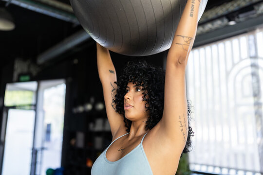 Determined athlete lifting fitness ball during workout session