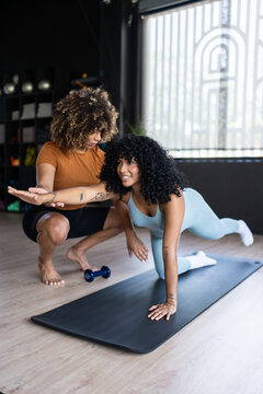 Personal trainer helping woman with bird dog exercise during