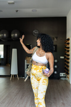Happy sportswoman waving goodbye at the gym after her workout