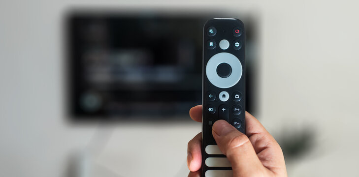 Person pointing smart remote control at television screen for streaming media entertainment concept
