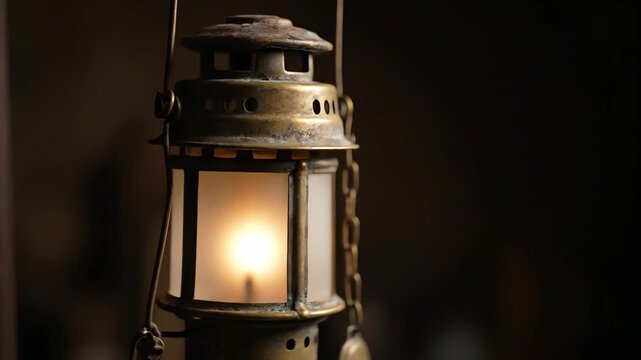 A beautifully crafted old brass lantern gently swinging in the wind, casting a warm, atmospheric glow for a vintage light concept