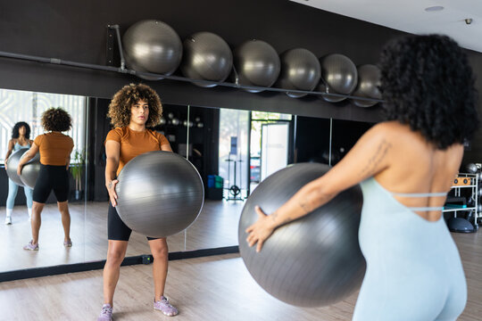 Two women are training with fitness balls in a gym