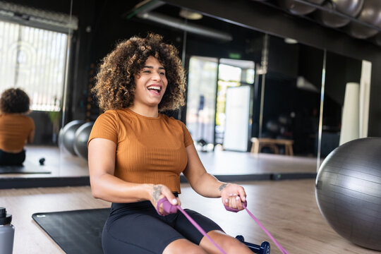 Happy sportswoman doing a rowing exercise using resistance band