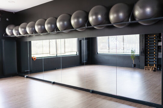 Empty gym with pilates balls and mirrors reflecting the room