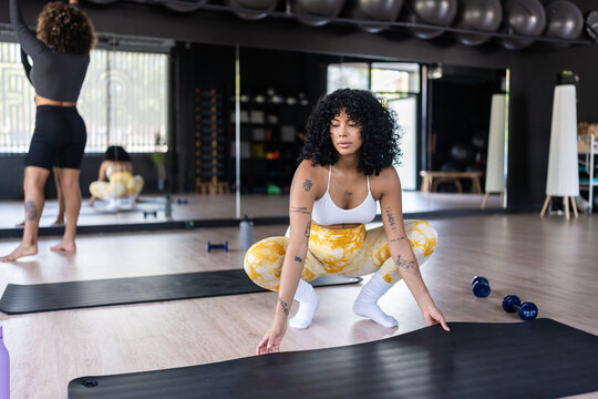 Young woman preparing exercise mat at the gym
