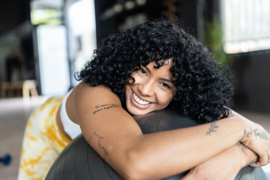 Happy athlete woman hugging fitness ball smiling at gym