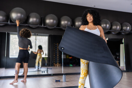 Fitness instructor preparing yoga mat for class in gym