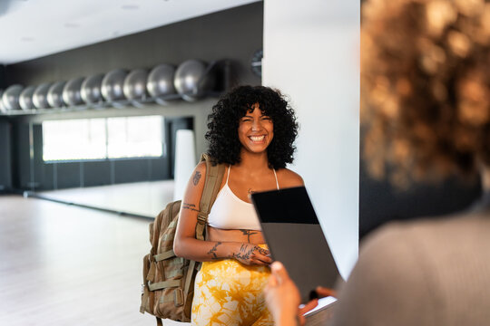 Happy customer arriving at the gym talking with receptionist