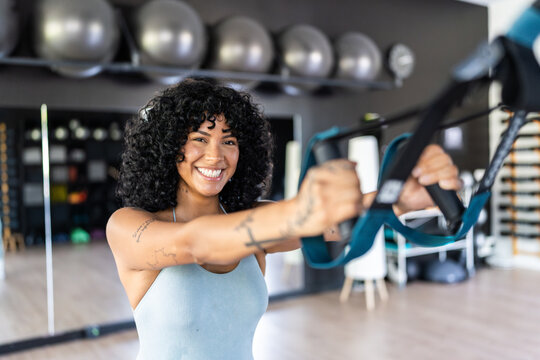 Young woman exercising with suspension training straps at gym