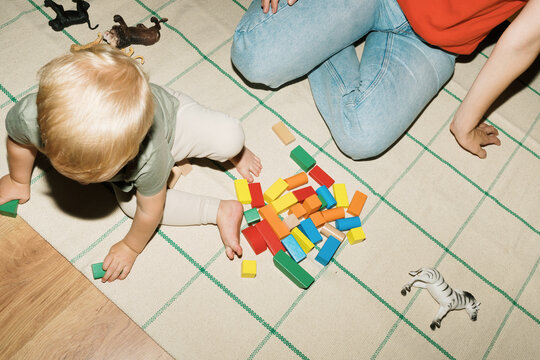 Child playing with colorful blocks on a rug at home