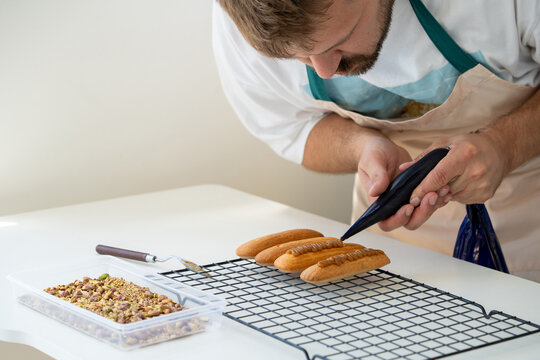 Baker Decorates Freshly Made Pastries in a Bright Kitchen