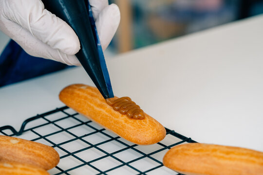 Person Decorating a Baked Pastry With Caramel Topping in a Kitchen