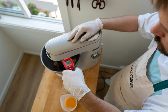 Baking Enthusiast Measures Temperature With Thermometer in Kitchen