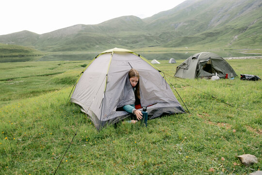 young woman coming out of her tent on backpacking trip