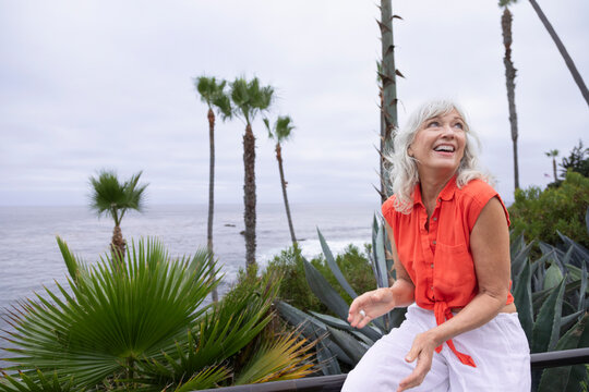 Beautiful grey haired woman smiling and overlooking the coast