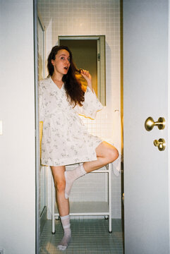 Playful Woman in Pajamas on Bathroom Shelf

