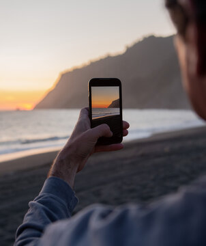 Man Taking Photo of Beautiful Sunset on California Beach 