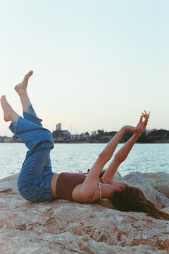 Young Woman Enjoys Sunset by the Water While Striking a Playful Pose