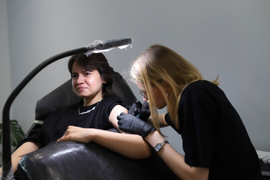woman pricks woman tattoo