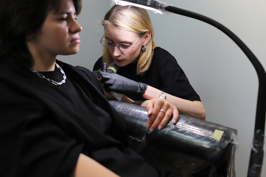 woman pricks woman tattoo