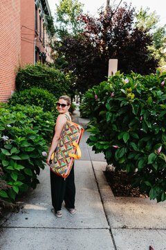 Woman walking on sidewalk with colorful yoga mat bag