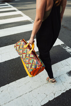 Close-up of woman carrying yoga mat bag in crosswalk